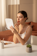 Mujer aplicando labial con espejo LED portátil